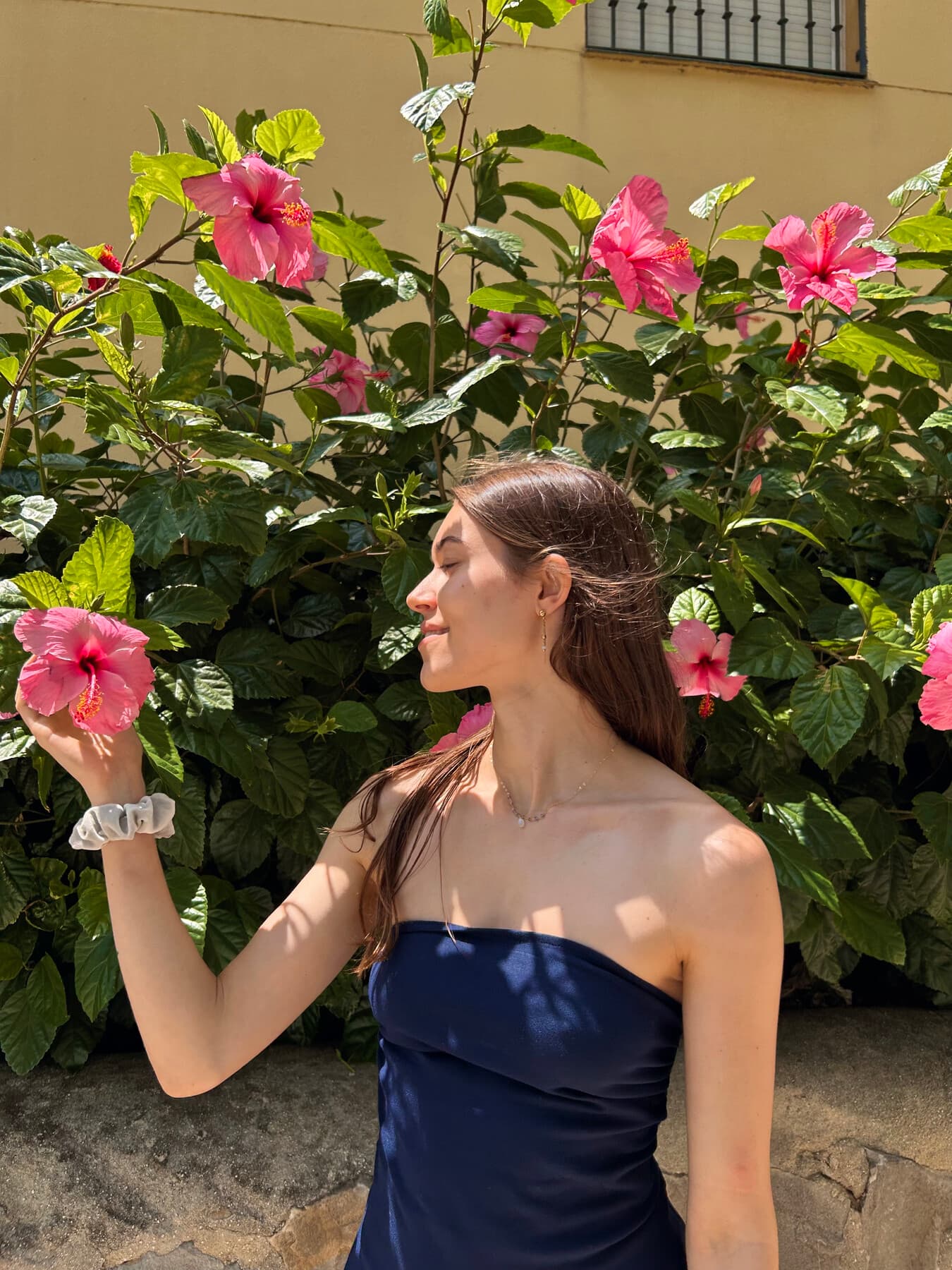 Vera holding a pink hibiscus flower